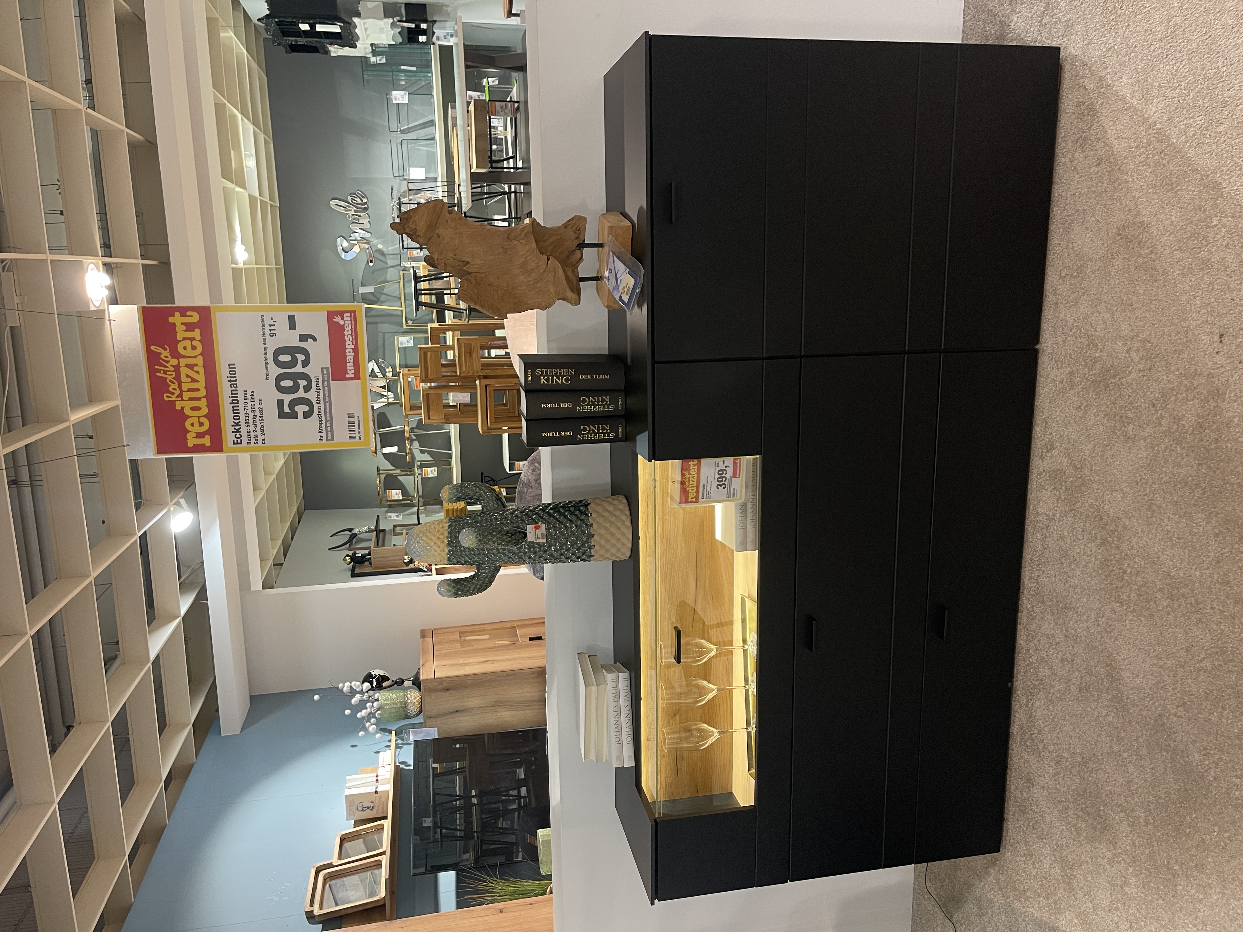 Schwarzes mattes Sideboard "Jacky" mit Glaselement, drei Schubladen und dekorativen Accessoires.
