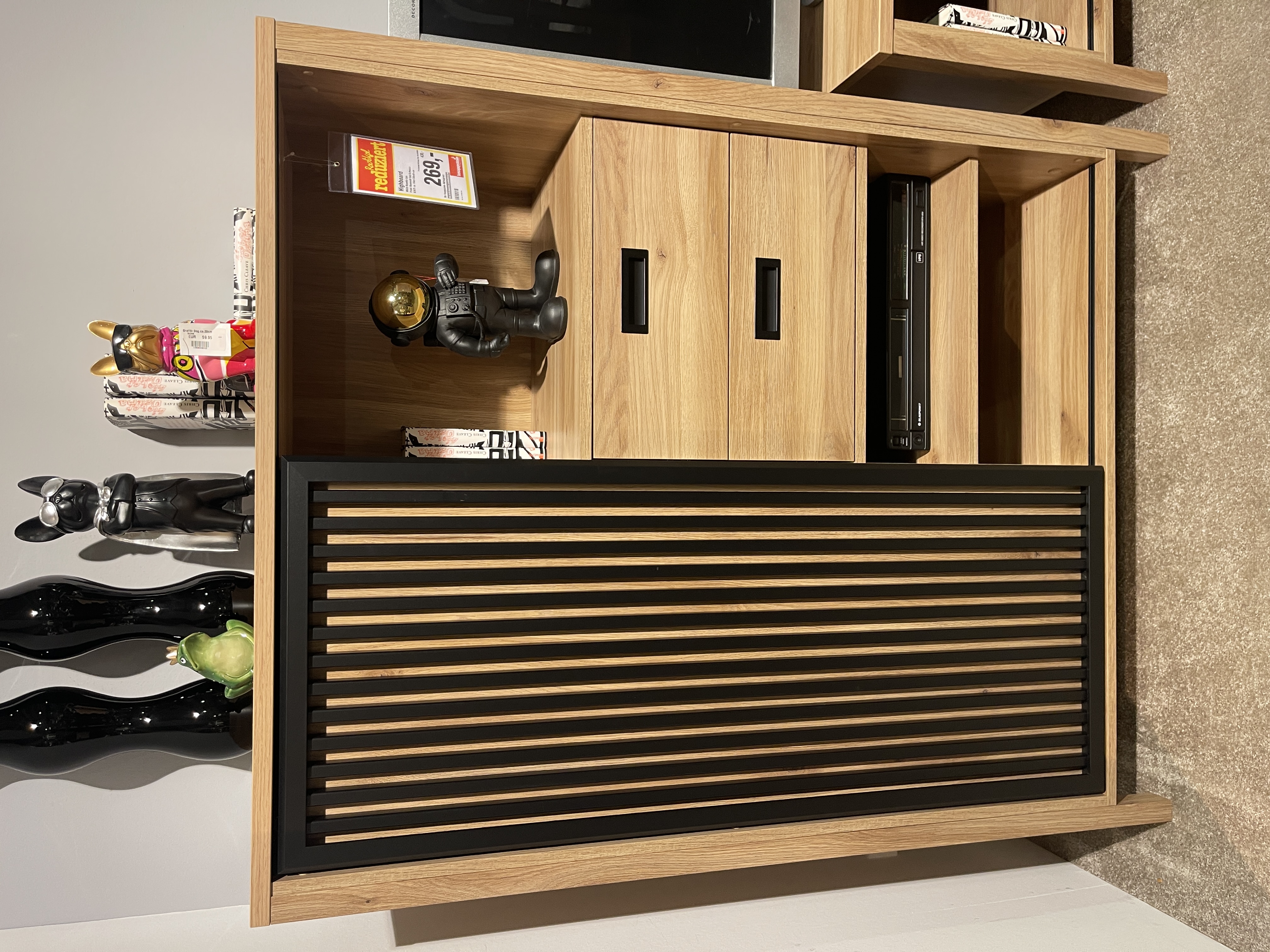 Highboard Jytana aus Eiche Schwarz, 104 cm breit, mit geschlossenen und offenen Fächern, dekoriert mit Figuren.