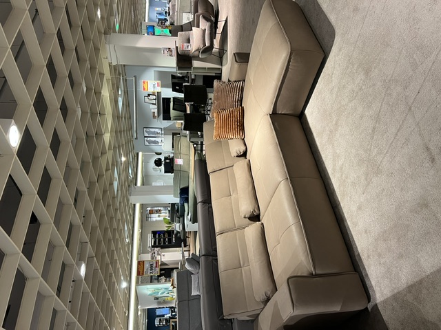 Polinova Garnitur VS-PN1210 Stone in beige, mit L-förmiger Couch und einem Kissen, ausgestellt im Möbelgeschäft.