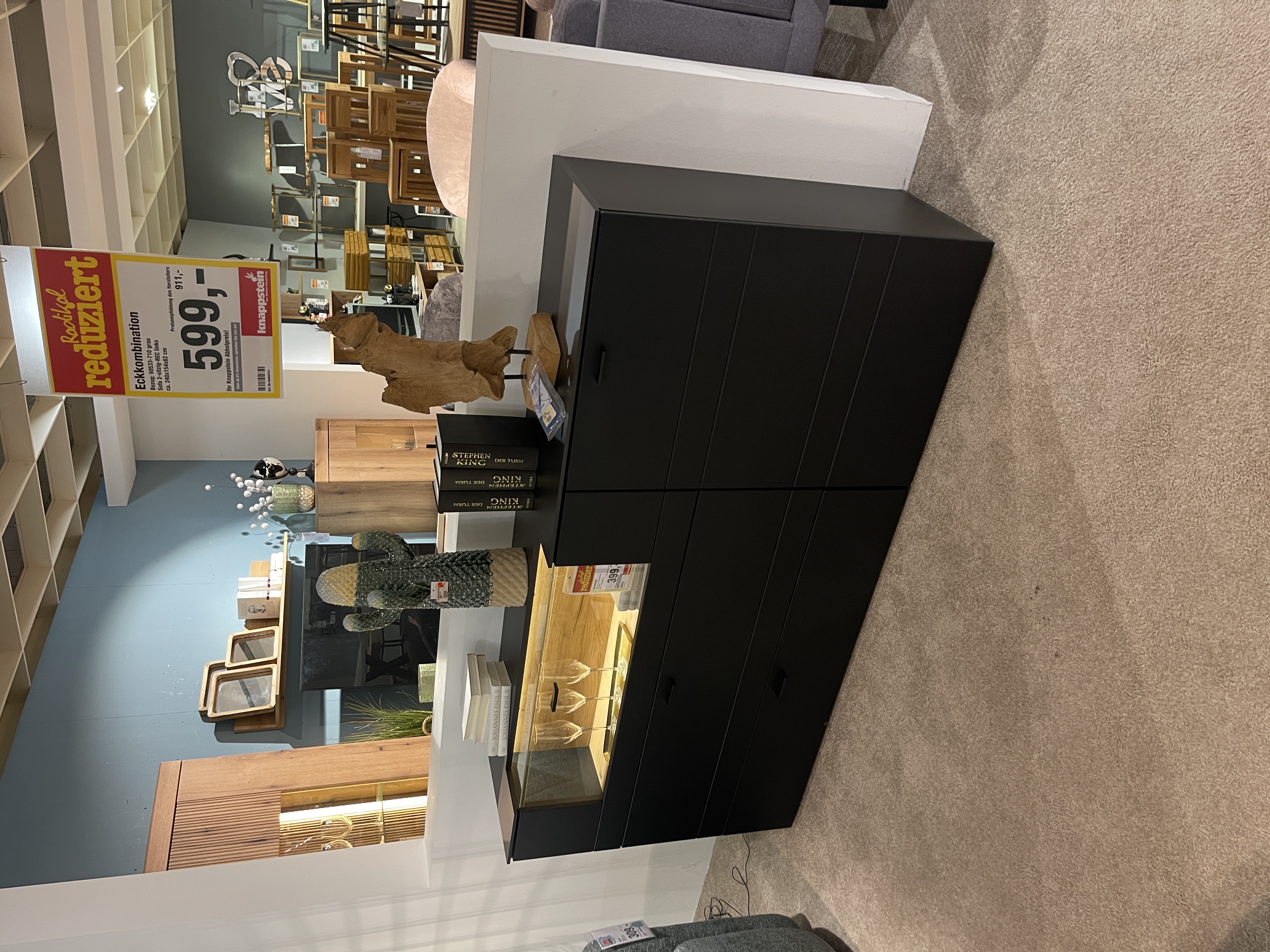 Schwarzes mattes Sideboard Jacky mit Glaselement, zwei Schubladen und Vitrine, in einem Möbelgeschäft ausgestellt.