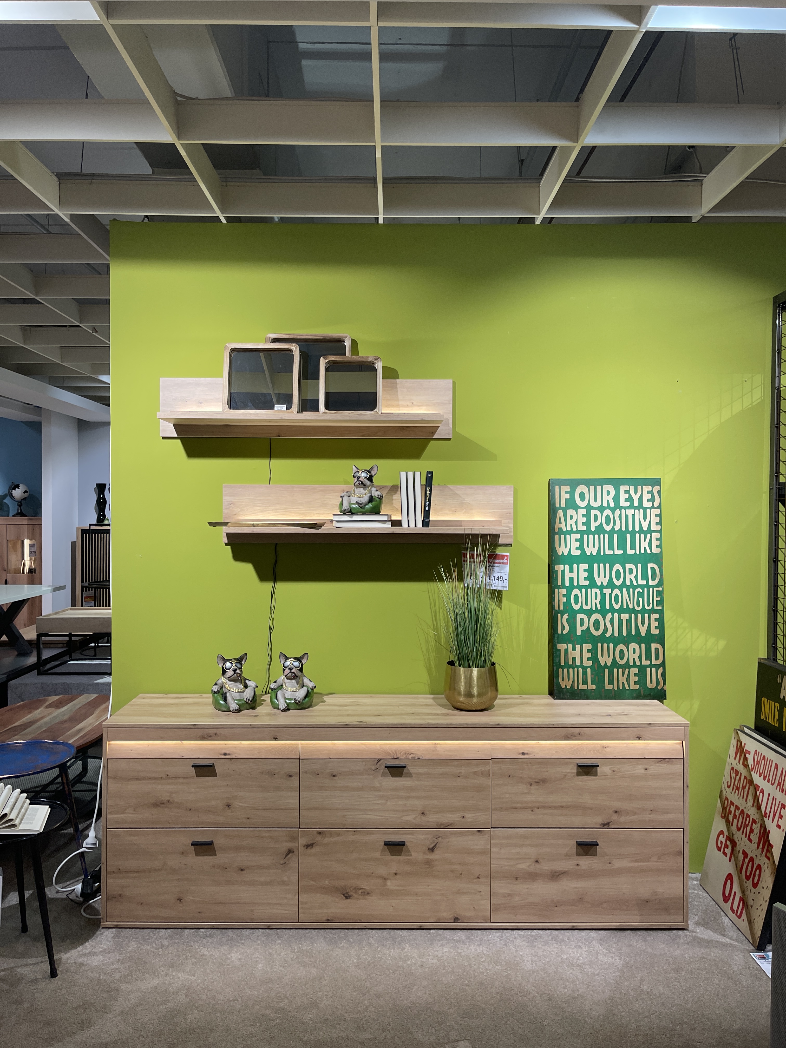 Wohnwand Boca in Eiche Artisan Dekor, mit Kommode und Wandregal, grüne Wand im Hintergrund.