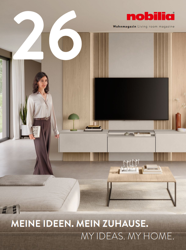 nobilia Wohnmagazin 2026 Moderne Wohnzimmereinrichtung mit TV-Wand und stilvoller Dekoration, Frau in eleganter Kleidung.