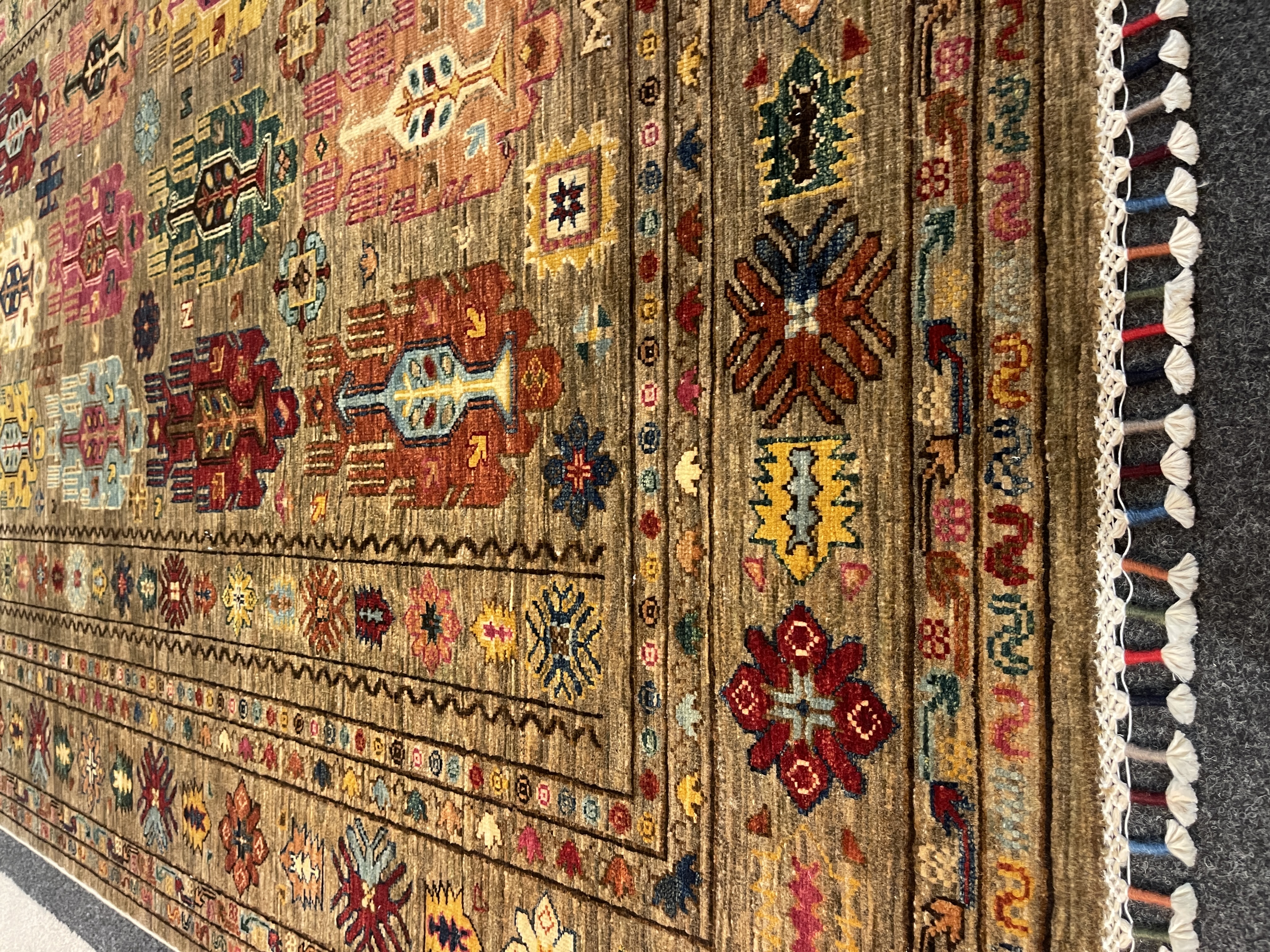 Gila Teppich in Grau mit bunten, geometrischen Mustern und Fransen, Größe ca. 251x176 cm.