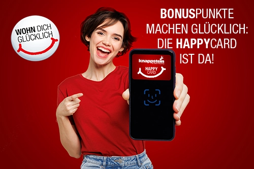 Frau in rotem Shirt hält ein Smartphone mit der HappyCard und lächelt. Hintergrund in Rot.