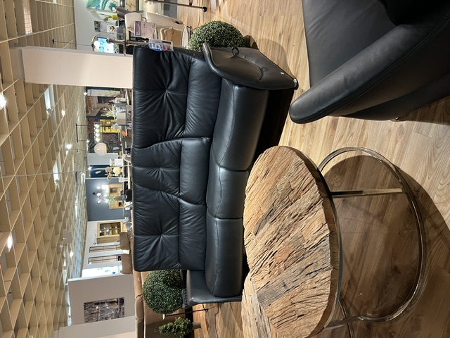 Trapezsofa mit zwei schwarzen Cumuly-Sesseln aus Leder und runder Holzablage.