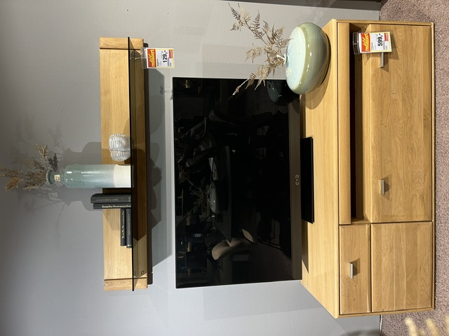 TV-Element Tarragona aus Eiche Bianco mit zwei Schubladen und Wandregal, dekoriert mit einer Vase und einem Glas.